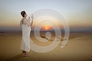 Asian Muslim man in ihram clothes standing and praying while raised arms