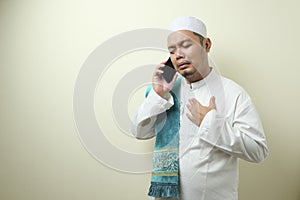 Asian Muslim man looks sad while receiving phone
