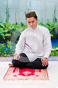 Asian Muslim man praying on carpet