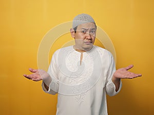 Asian muslim man shows refusal or denial gesture, shoulder shrug, I don`t know expression