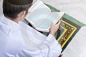 Asian Muslim man sitting and reading the Quran
