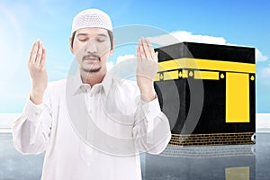 Asian Muslim man standing and praying with Kaaba view