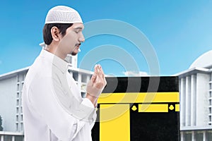 Asian Muslim man standing and praying with Kaaba view