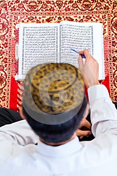 Asian Muslim man studying Koran or Quran