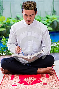 Asian Muslim man studying Koran or Quran