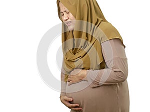 Asian muslim pregnant mother feeling pain in her stomach, woman wearing hijab with big belly, isolated