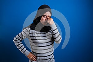 Asian muslim teenage girl holding her head and close her eyes, painful expression