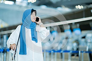 An Asian Muslim wearing a blue hijab is preparing for a vacation and she is at the international airport.
