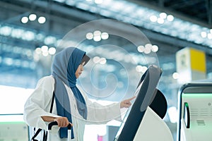 An Asian Muslim wearing a blue hijab is preparing for a vacation and she is at the international airport.