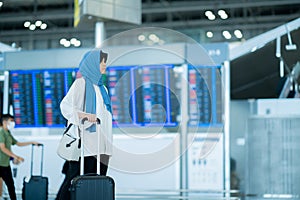 An Asian Muslim wearing a blue hijab is preparing for a vacation and she is at the international airport.