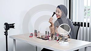 Asian muslim woman beauty blogger holding makeup brush and applies to review how to use makeup brush