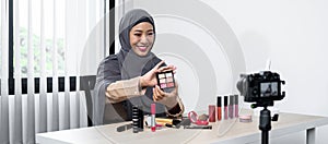 Asian muslim woman beauty blogger looking at the camera to review eye shadow showing on her hand