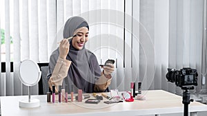 Asian muslim woman beauty blogger tutorial by eye shadow makeup on her eyes and making videos