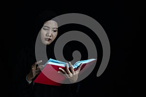 Asian Muslim woman in black Muslim veil hijab reading the Qur'an