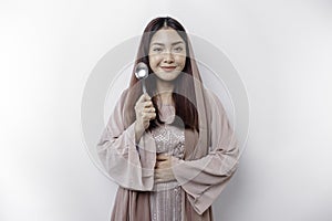 An Asian Muslim woman is fasting and hungry and holding cutlery while looking aside thinking about what to eat