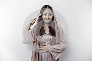 An Asian Muslim woman is fasting and hungry and holding cutlery while looking aside thinking about what to eat