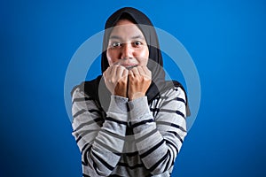 Asian muslim woman looks scared while biting her nails