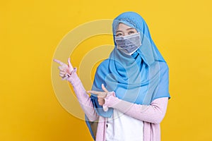 Asian muslim woman in medical mask Coronavirus pandemic disease pointing to copy space isolate background. COVID-19 virus epidemic