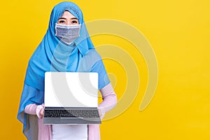 Asian muslim woman in medical mask Coronavirus pandemic disease using laptop computer isolate background. COVID-19 virus epidemic