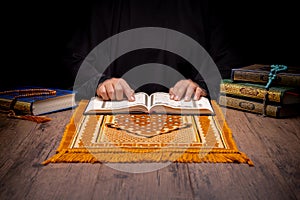 A Asian Muslim woman is sitting and reading the Quran at the wooden table at his house