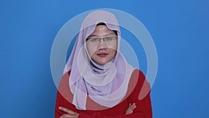 Asian muslim woman smiling at camera and asking for silent, finger over lip, shushing gesture, keep it in secret