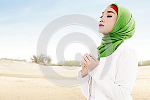 Asian Muslim woman in veil praying with prayer beads on her hands