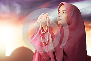 Asian Muslim woman in veil praying with prayer beads on her hands