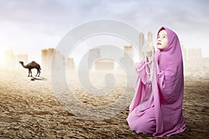 Asian Muslim woman in veil sitting and praying with prayer beads on her hands