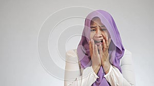Asian muslim woman wearing hijab shocked with mouth opened, frightened to see something bad