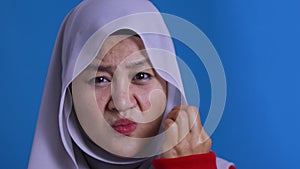 Asian muslim woman wearing hijab shows zip mouth gesture, keep secret don`t tell anyone