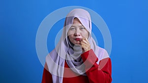 Asian muslim woman wearing hijab shows zip mouth gesture, keep secret don`t tell anyone