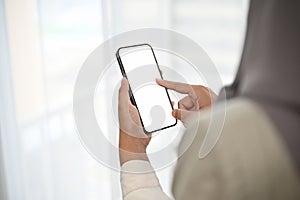 Asian Muslim woman wearing hijab using her mobile phone. Phone white screen mockup