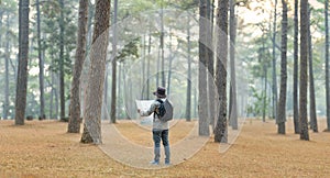 Asian naturalist looking at the map for direction while exploring wildlife in the pine forest for surveying and discovering the