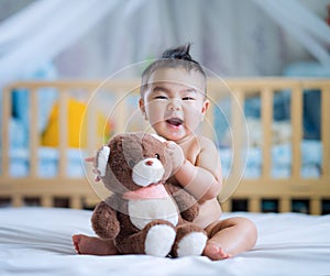 Asian new born baby sit and hug a teddy bear