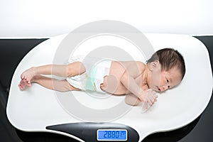 Asian newborn baby laying on the scales