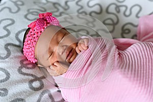 Asian newborn baby sleepin in pink cloth wearing headband