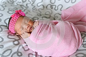 Asian newborn baby sleepin in pink cloth wearing headband