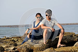 Asian newly married couple sitting on the coral of a sea beach having a romantic time