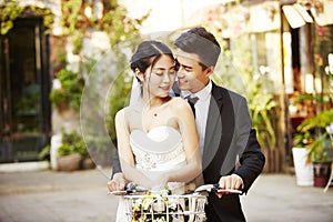 Asian newly wed couple riding a bicycle