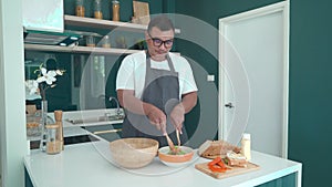 Asian newlywed prepare healthy breakfast for couple, man with glasses cook vegatable salad in wooden bowl making sandwiches for wi