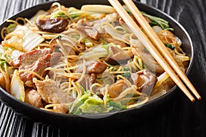 Asian noodles with fried pork belly, mushrooms and napa cabbage in soy sauce close-up in a plate. horizontal