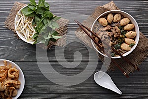 Asian noodles with pork, pork balls, pork crackling and vegetables on dark background. Close up Thai boat noodle culture style top