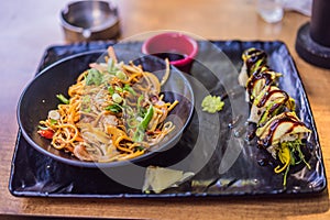 Asian noodles and sushi in black bowl