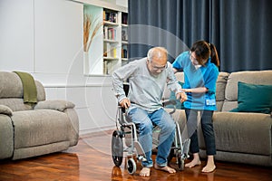 Asian nurse assisting helping senior man patient get up from wheelchair for practice walking