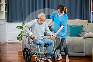 Asian nurse assisting helping senior man patient get up from wheelchair for practice walking
