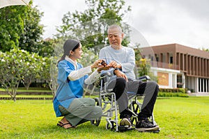 Asian nurse caring for an old man in the garden at home, nurse caregiver supporting health insurance at home