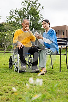 Asian nurse caring for an old man in the garden at home, nurse caregiver supporting health insurance at home