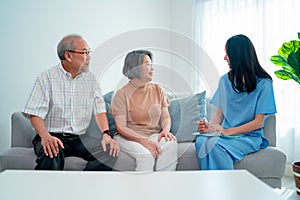 Asian nurse or doctor discuss with senior man and woman in living room with concept of home care worker support and modern