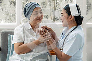 Asian nurse gentlely hug senior cancer patient who wearing headscraf after chemotherapy to encourage patein to fight with sickness