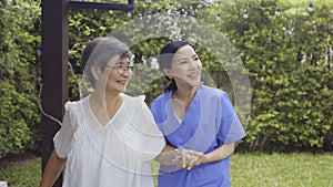 Asian nurse and patient walking in backyard